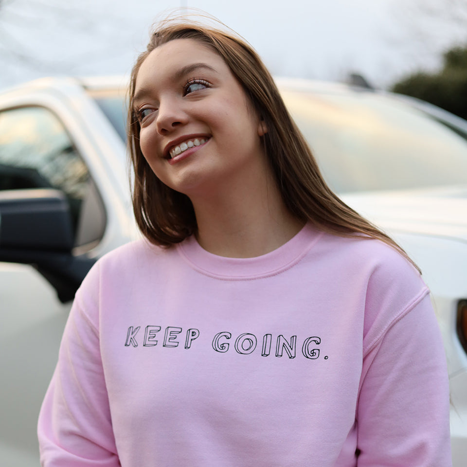 The Keep Going Sweatshirt in Pink with model wearing it looking off to their right. 